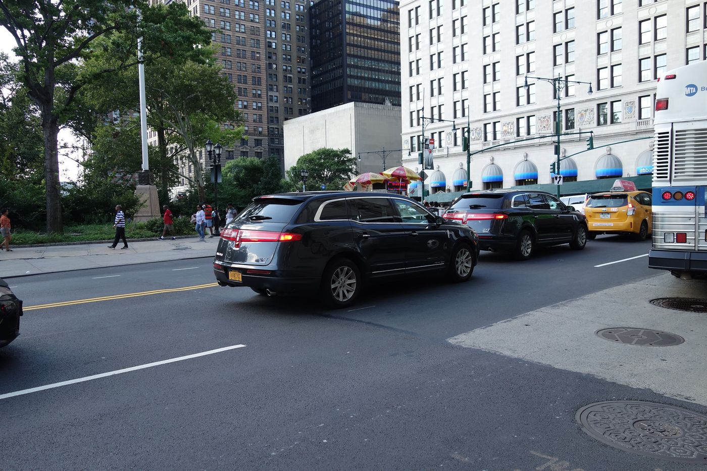 Black sedans and SUVs parked along a city kerb.