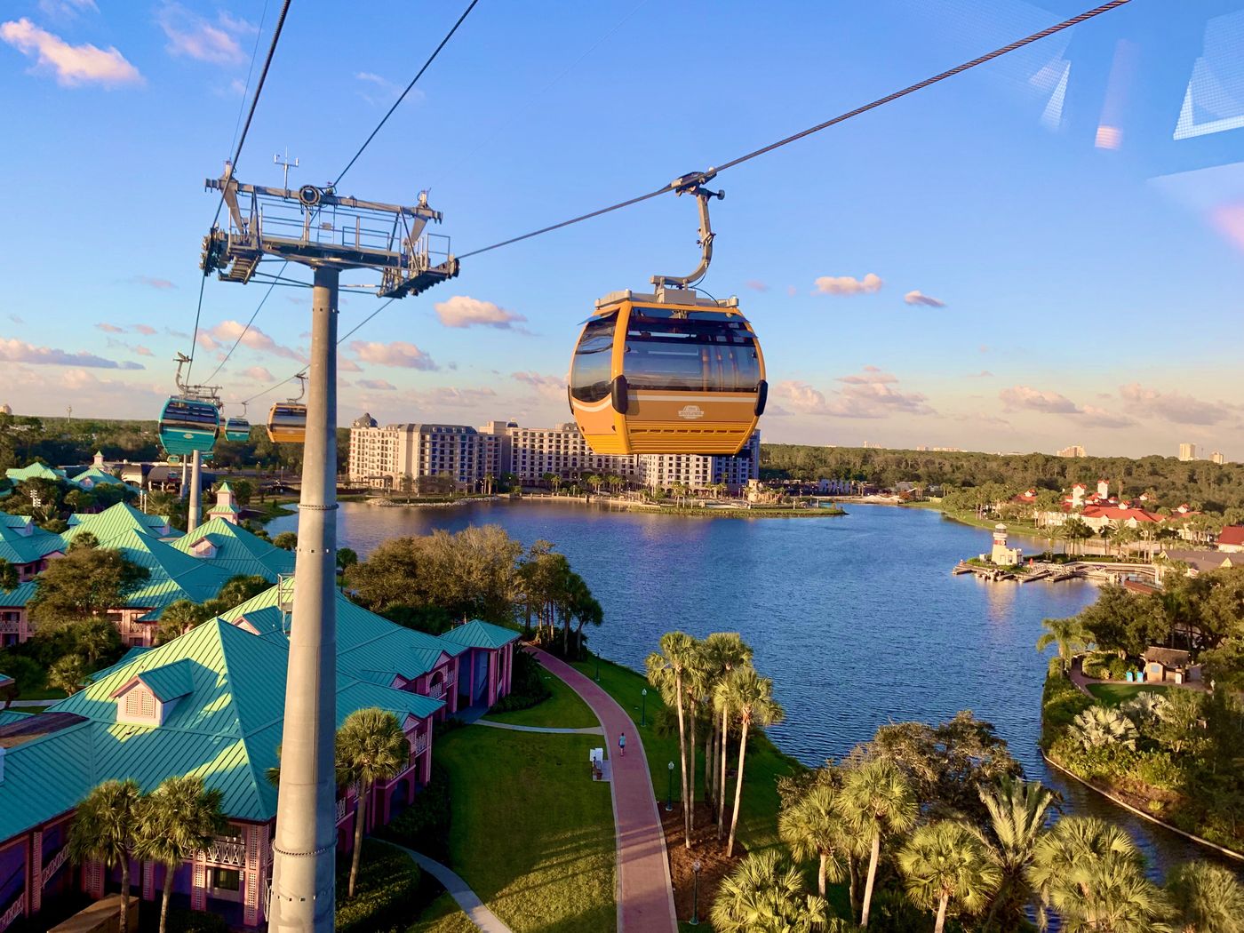 Disney Skyliner gondolas crossing a lake above a resort.