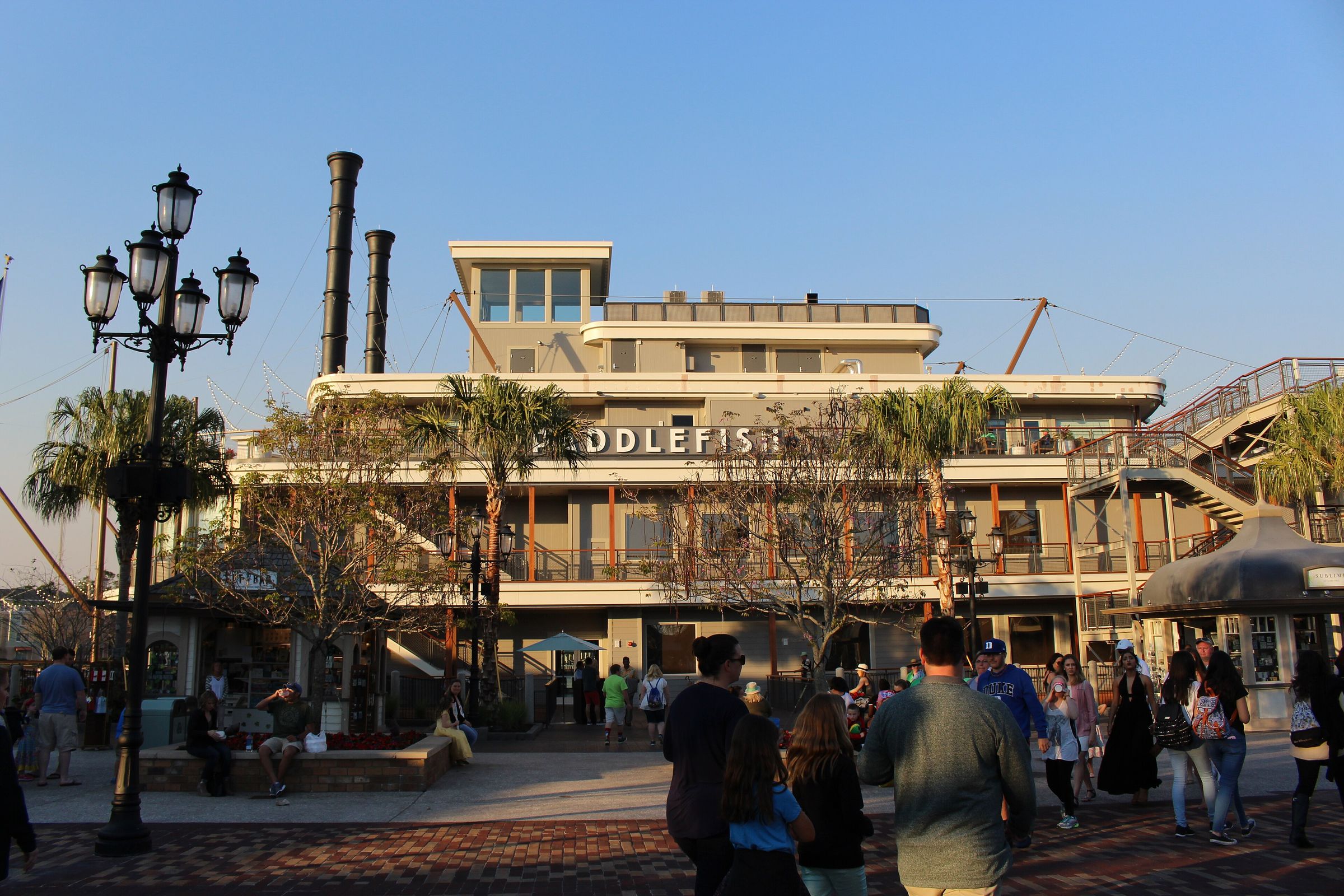 Visitors walking the waterfront promenade at Disney Springs.