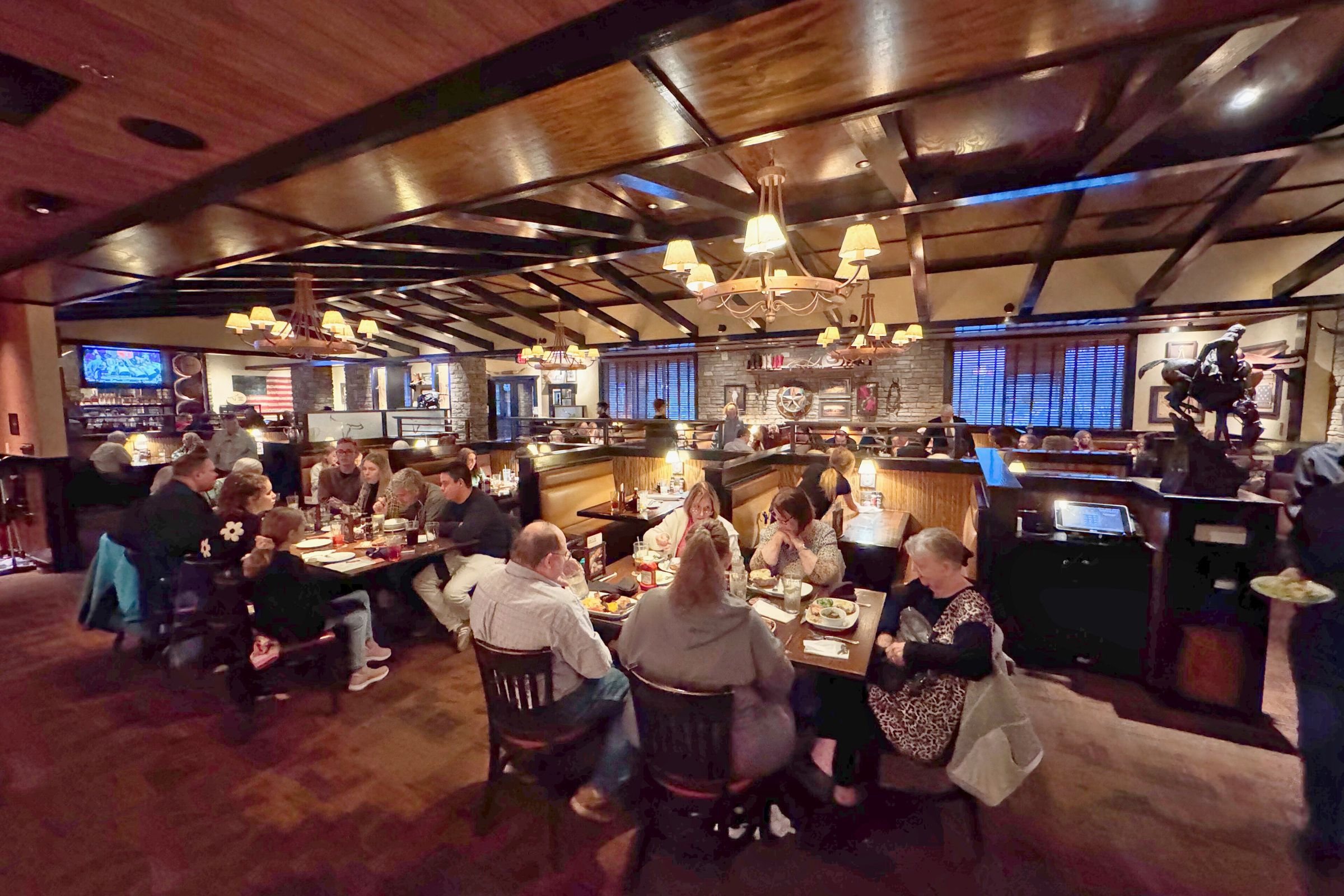 A busy restaurant dining room with wooden booths and warm lighting.