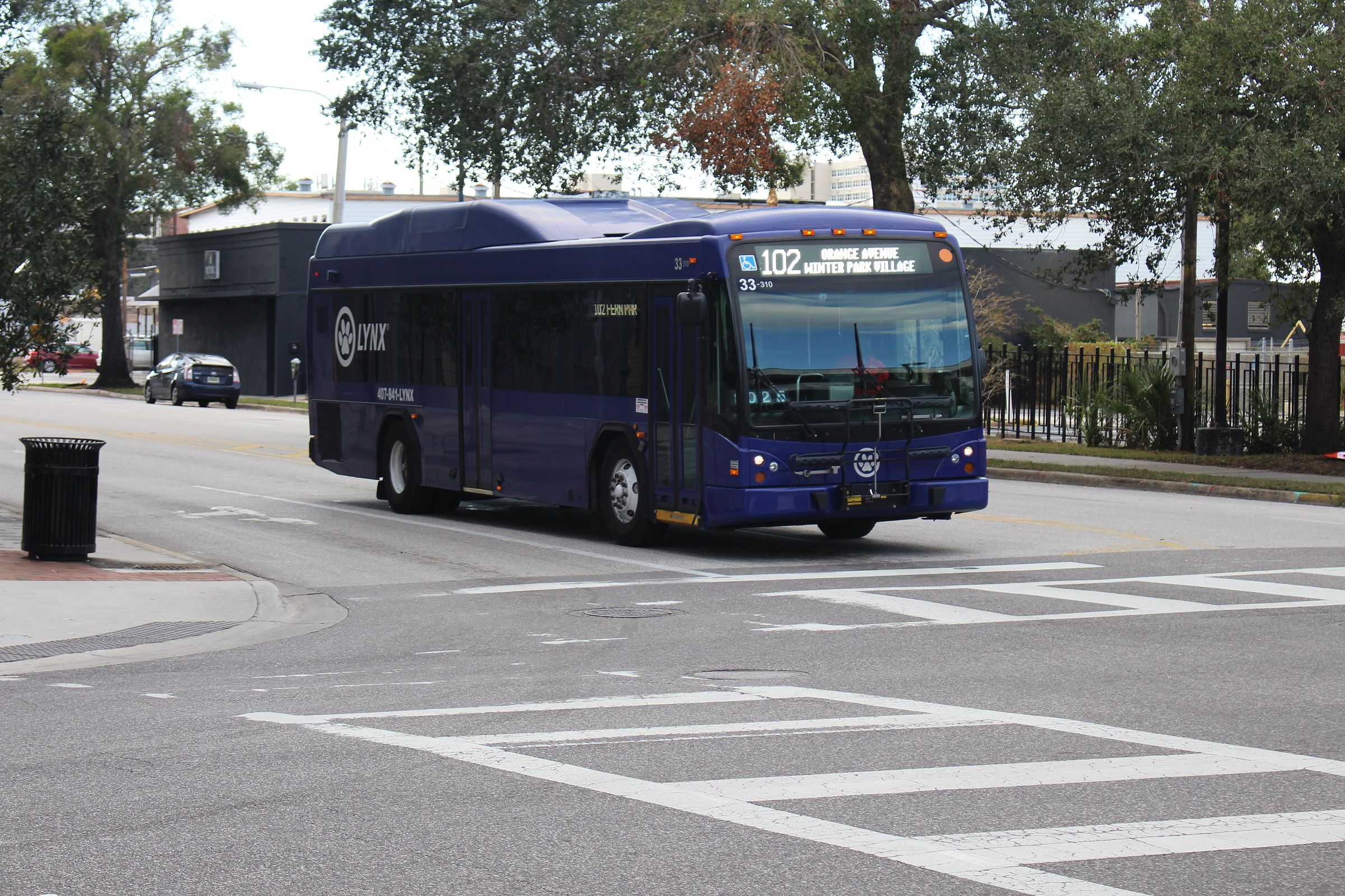 A purple Lynx Route 102 bus turning through an Orlando intersection.