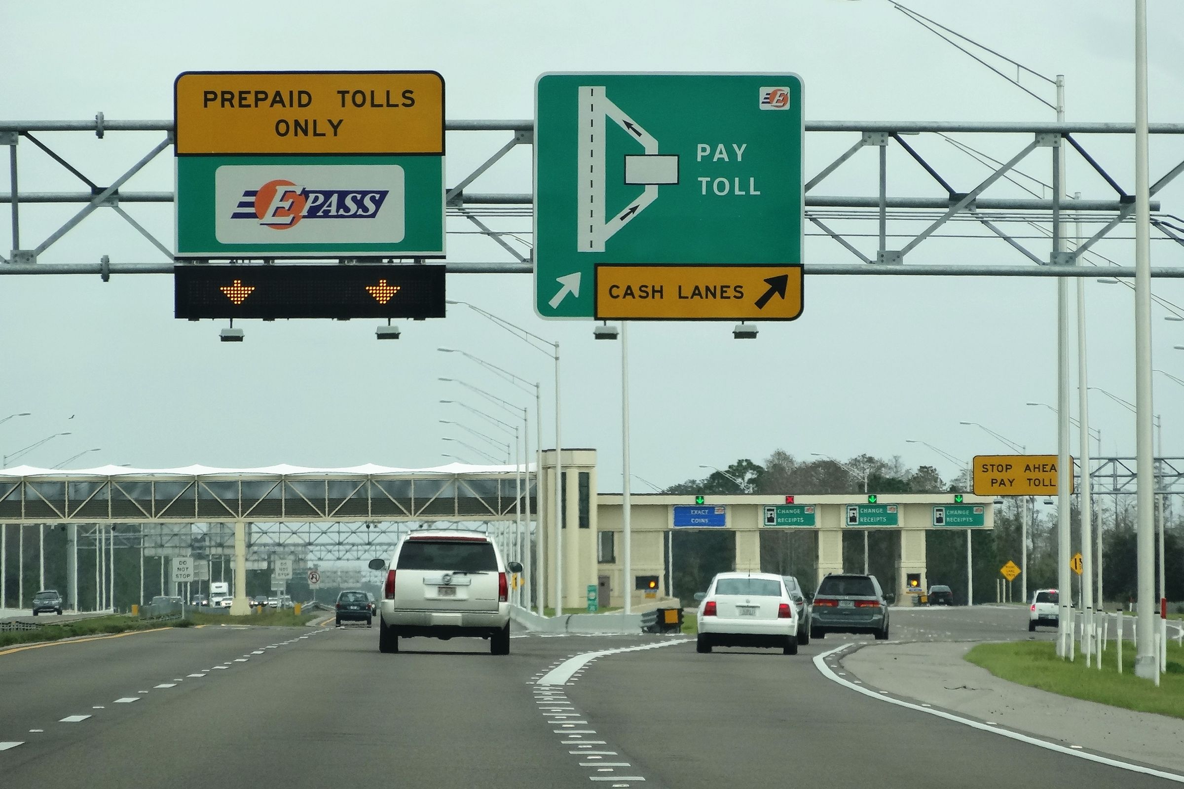 Overhead gantry signs reading E-PASS prepaid tolls only, pay toll, and cash lanes.