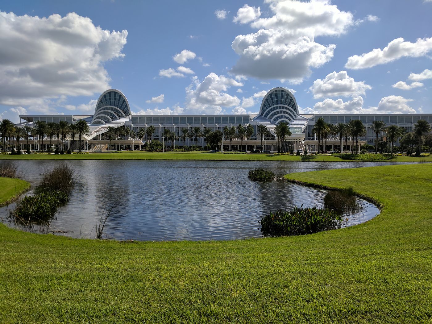 The Orange County Convention Center seen across a lake and lawn.