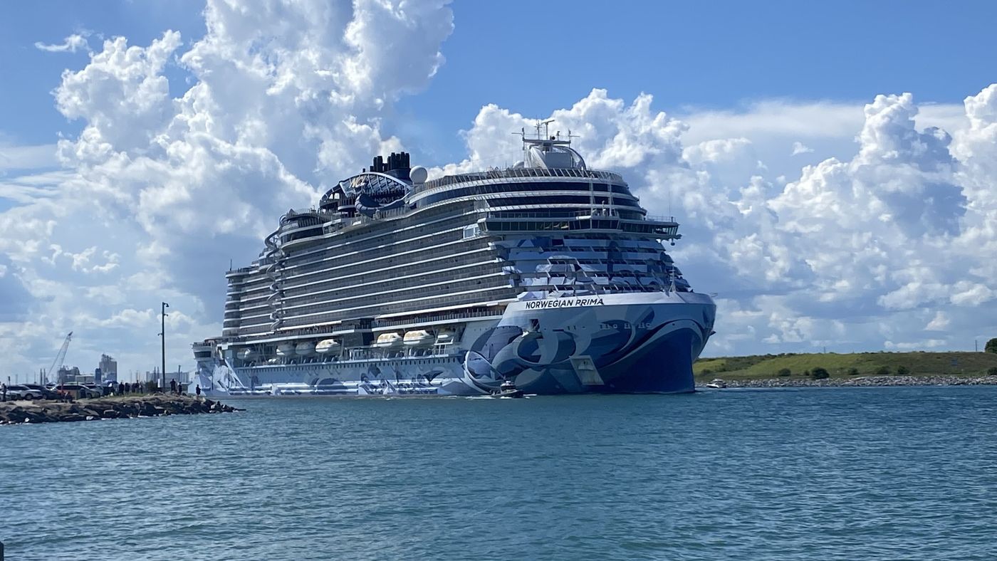 A large cruise ship berthed at Port Canaveral under a cloudy sky.