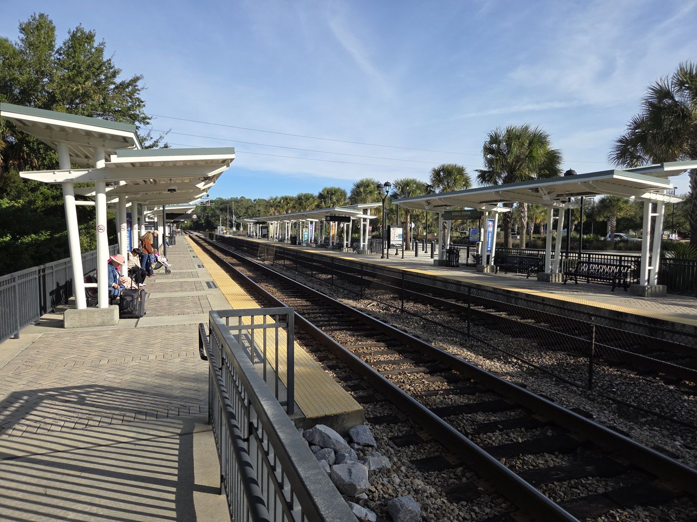 An empty SunRail platform with canopies and palm trees.