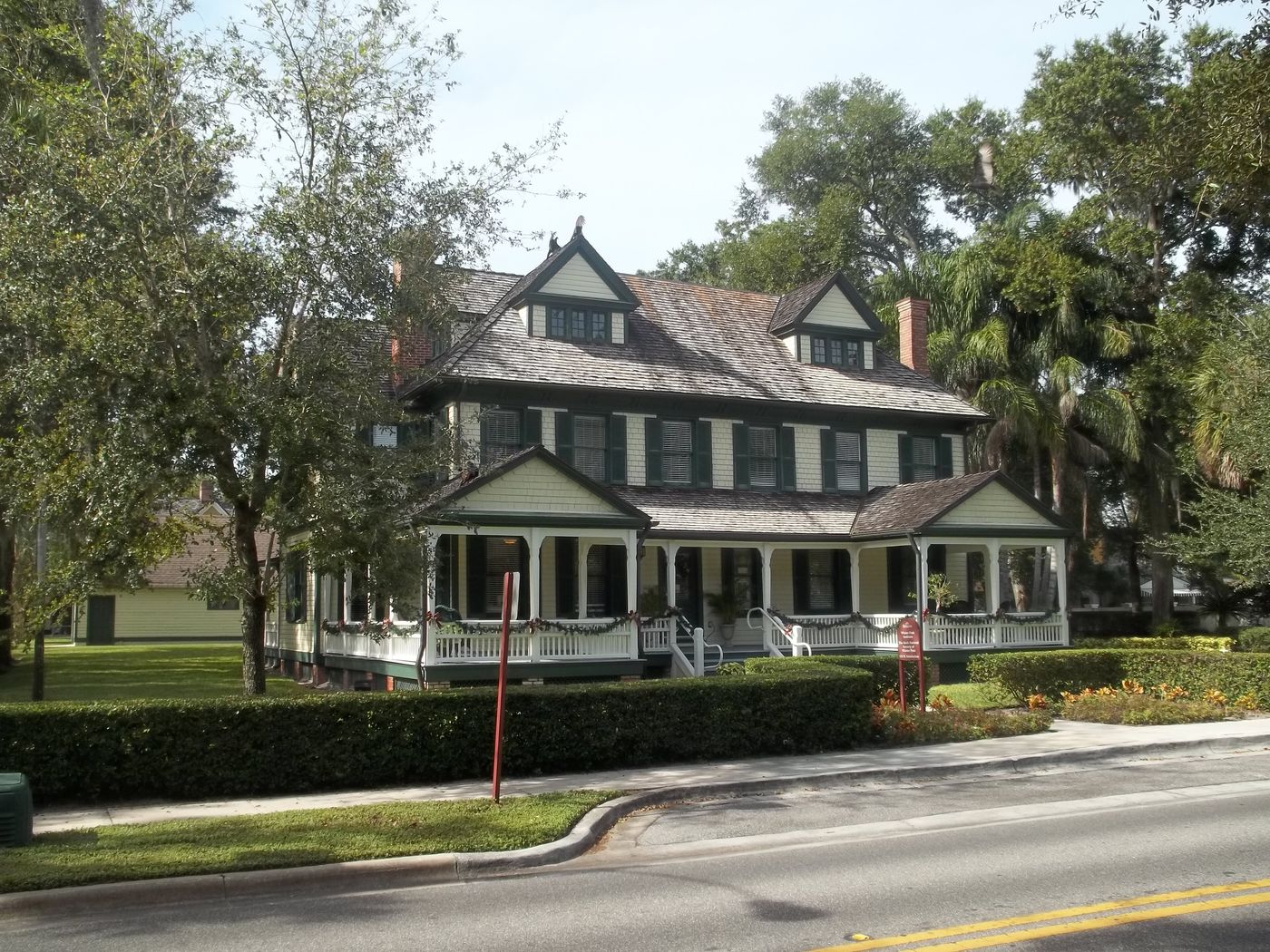 A historic house behind live oaks on a Winter Park street.